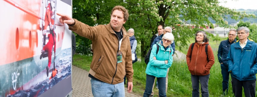 a man pointing at a poster on a wall.